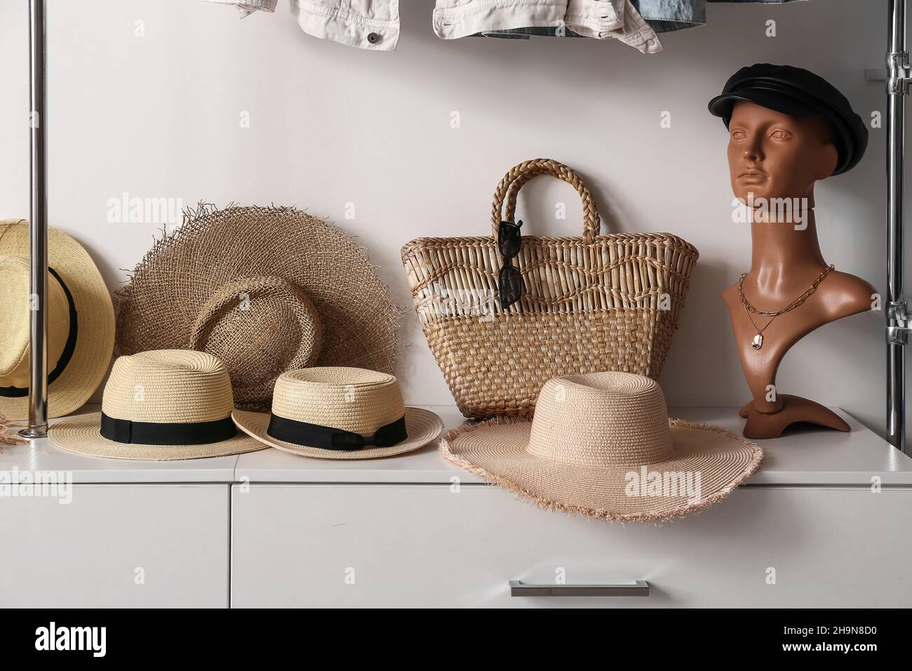 Mannequin with leather cap, different straw hats and bag on shelf in