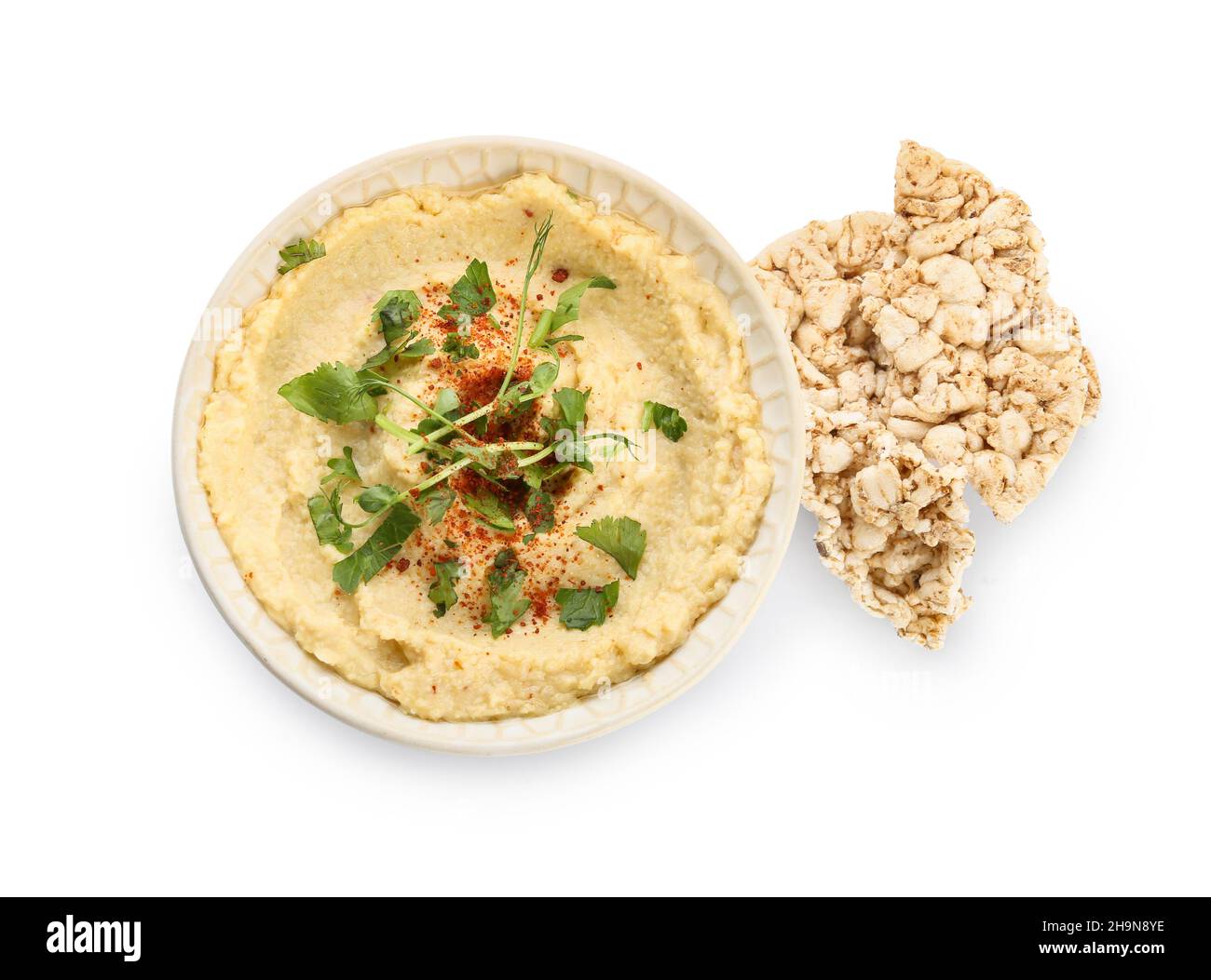 Bowl with delicious hummus and rice crackers on white background Stock