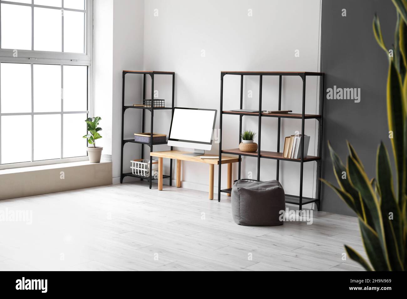 Interior of light room with table, computer screen and shelving units ...