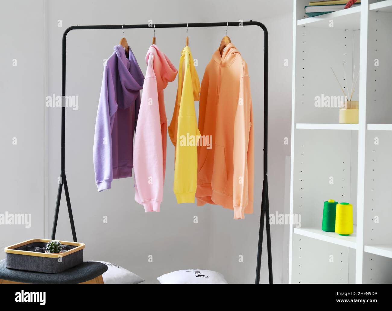 Hoddies On A Rack Rack with stylish hoodies near light wall in room Stock Photo - Alamy