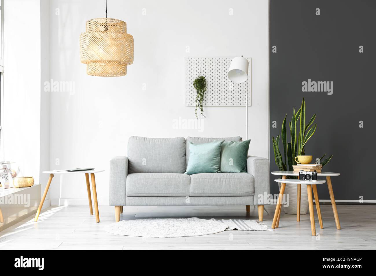 Interior of light living room with grey sofa and tables Stock Photo - Alamy