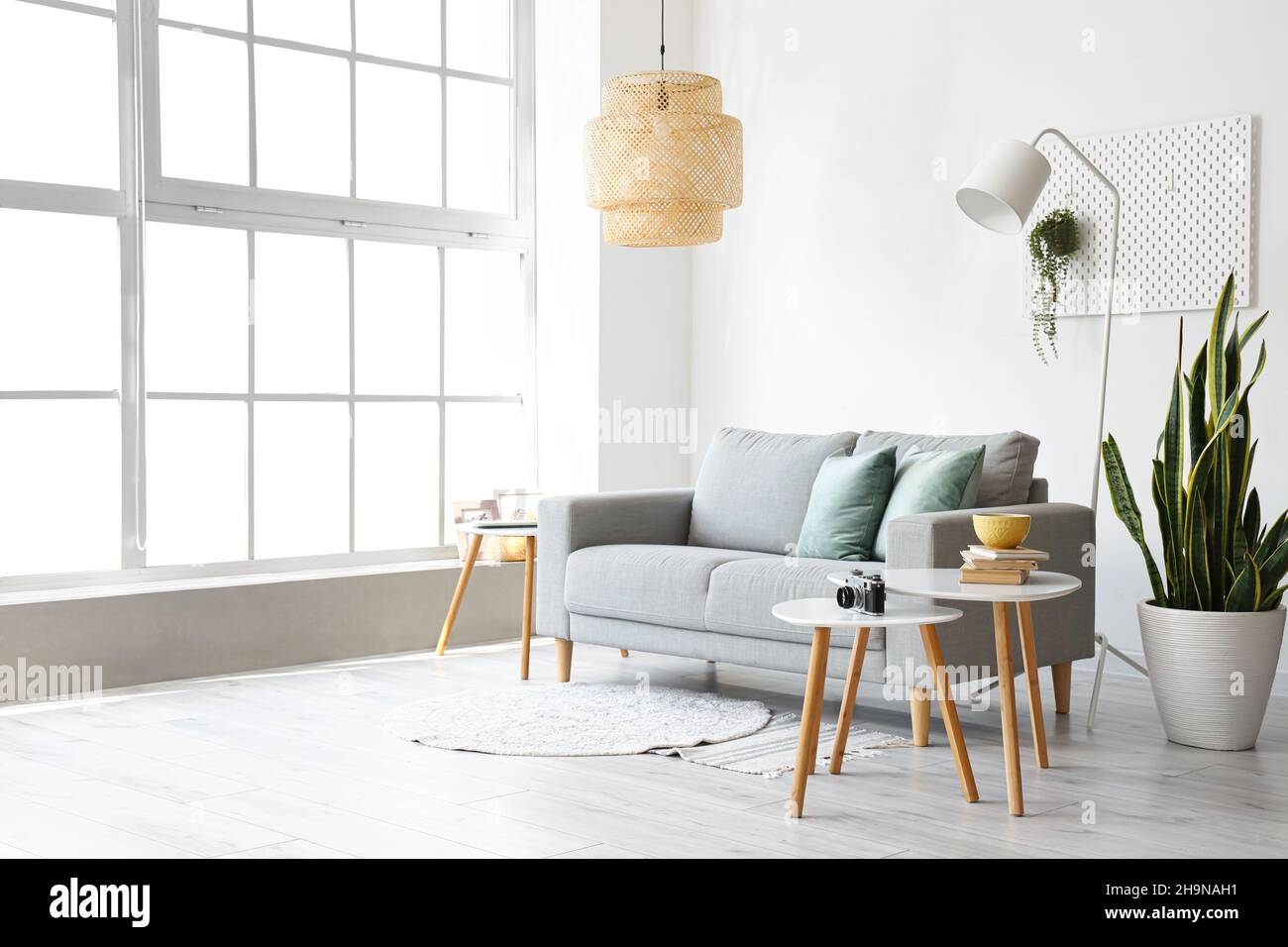 Interior of light living room with grey sofa and tables Stock Photo - Alamy