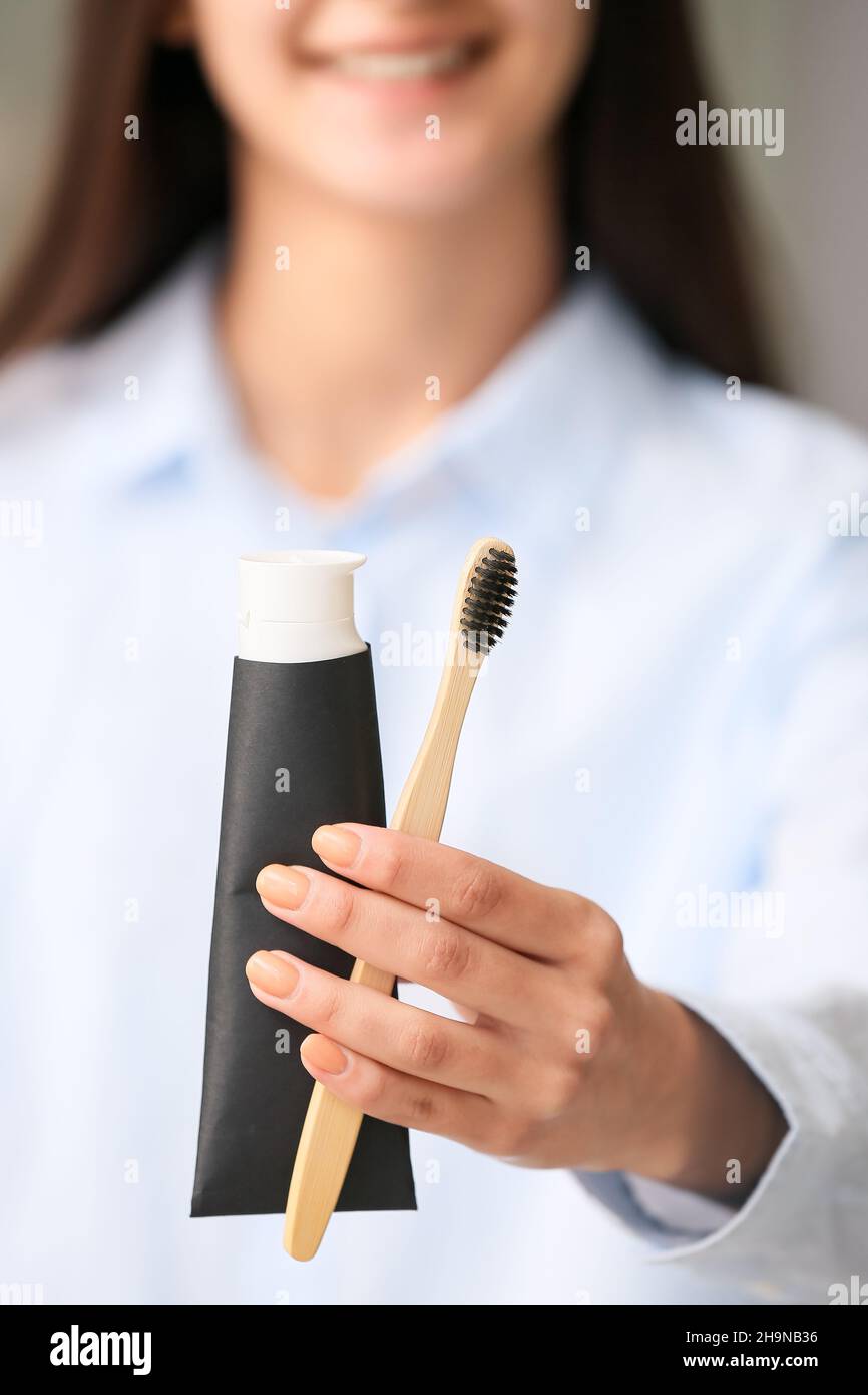 Woman with tube of black tooth paste and bamboo brush at home, closeup Stock Photo