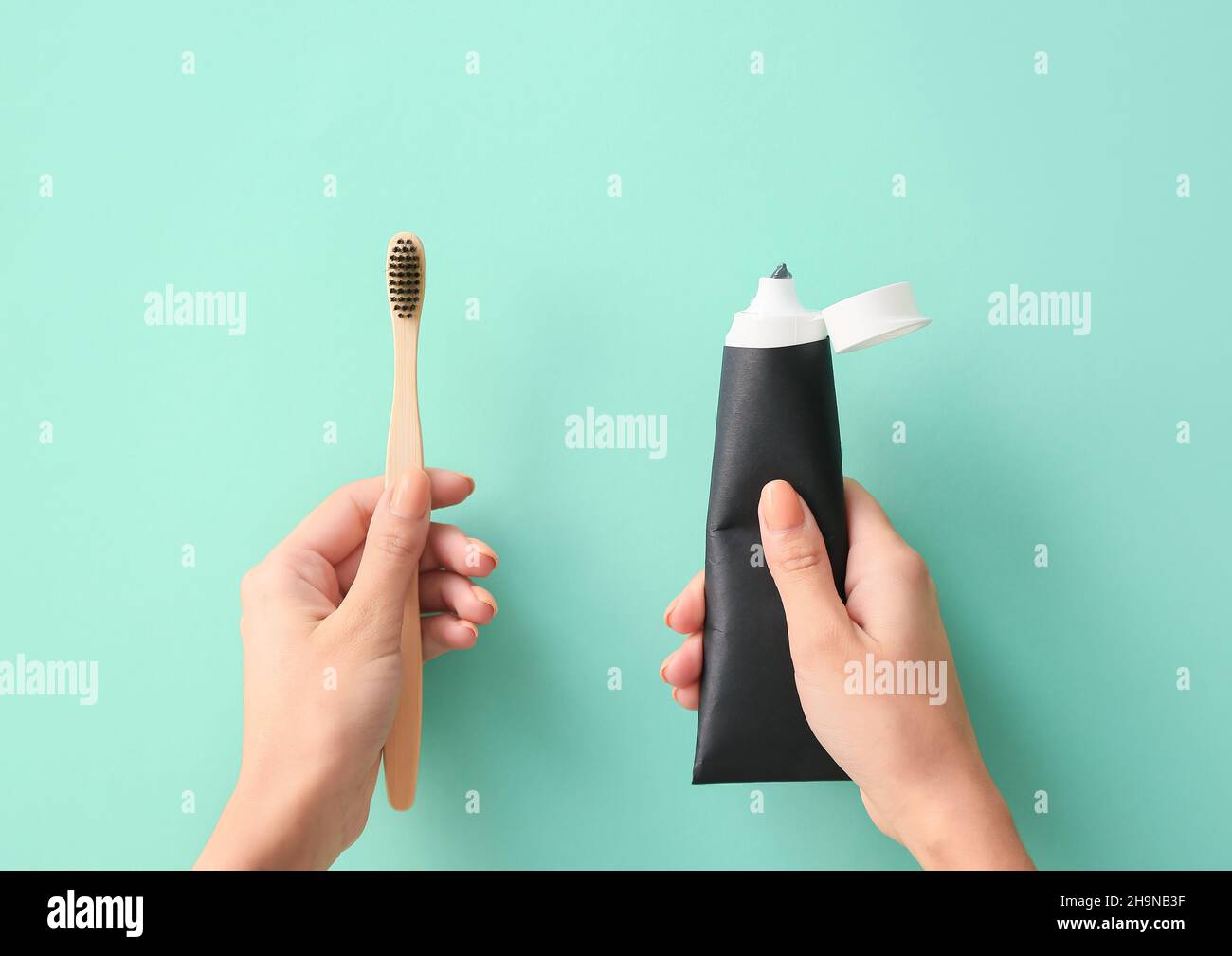 Woman with tube of black tooth paste and bamboo brush on blue background Stock Photo