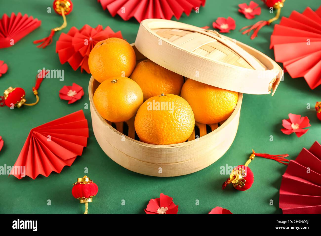 Box with tasty tangerines and Chinese symbols on color background Stock