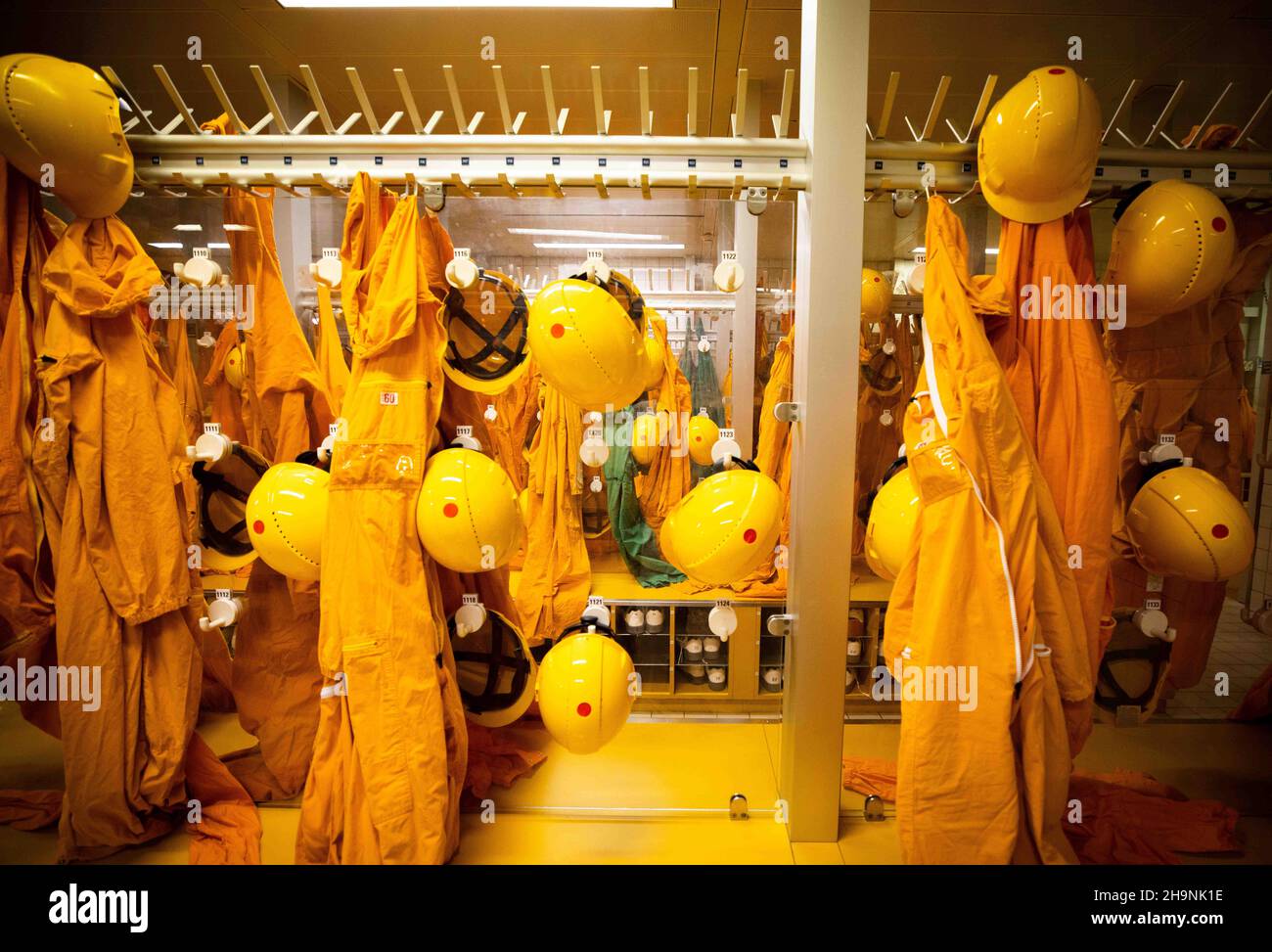 Brokdorf, Germany. 02nd Dec, 2021. Orange overalls and yellow hard hats  hang on a coat rack in the entrance to the reactor building at the Brokdorf nuclear  power plant. After almost 35