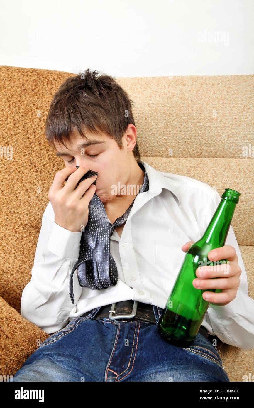 Drunken Teenager with Bottle of the Beer on the Sofa at the Home Stock Photo