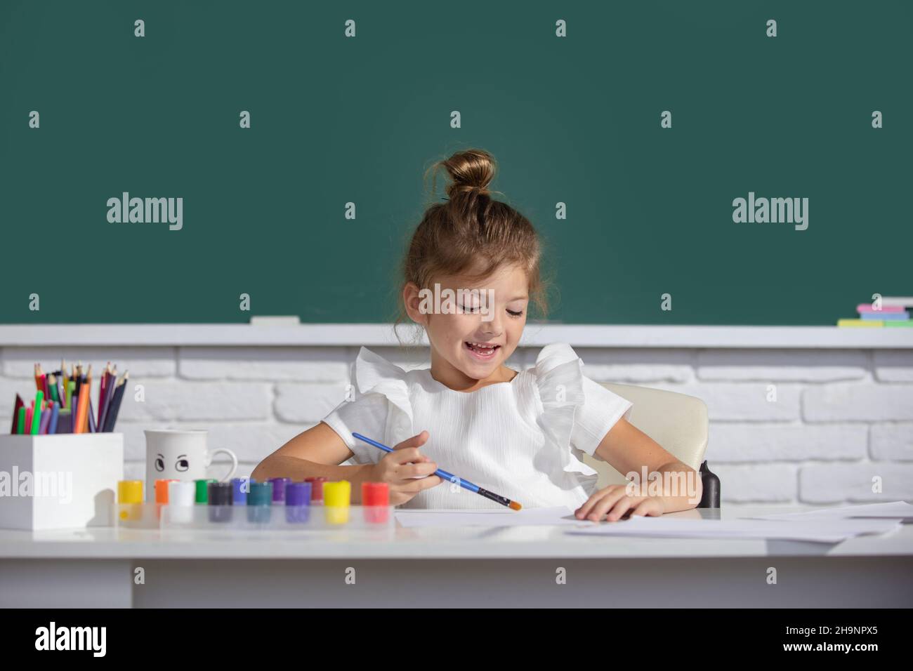 Little girls drawing a colorful pictures with pencil crayons in school