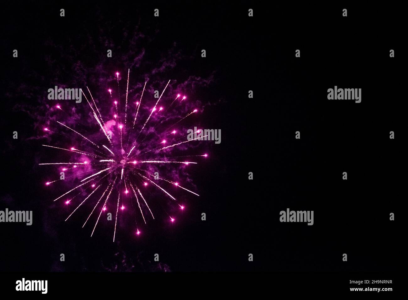 round fireworks and purple fireworks against the black sky. Christmas fireworks in the night sky. Christmas fireworks. Color of the year very peri Stock Photo