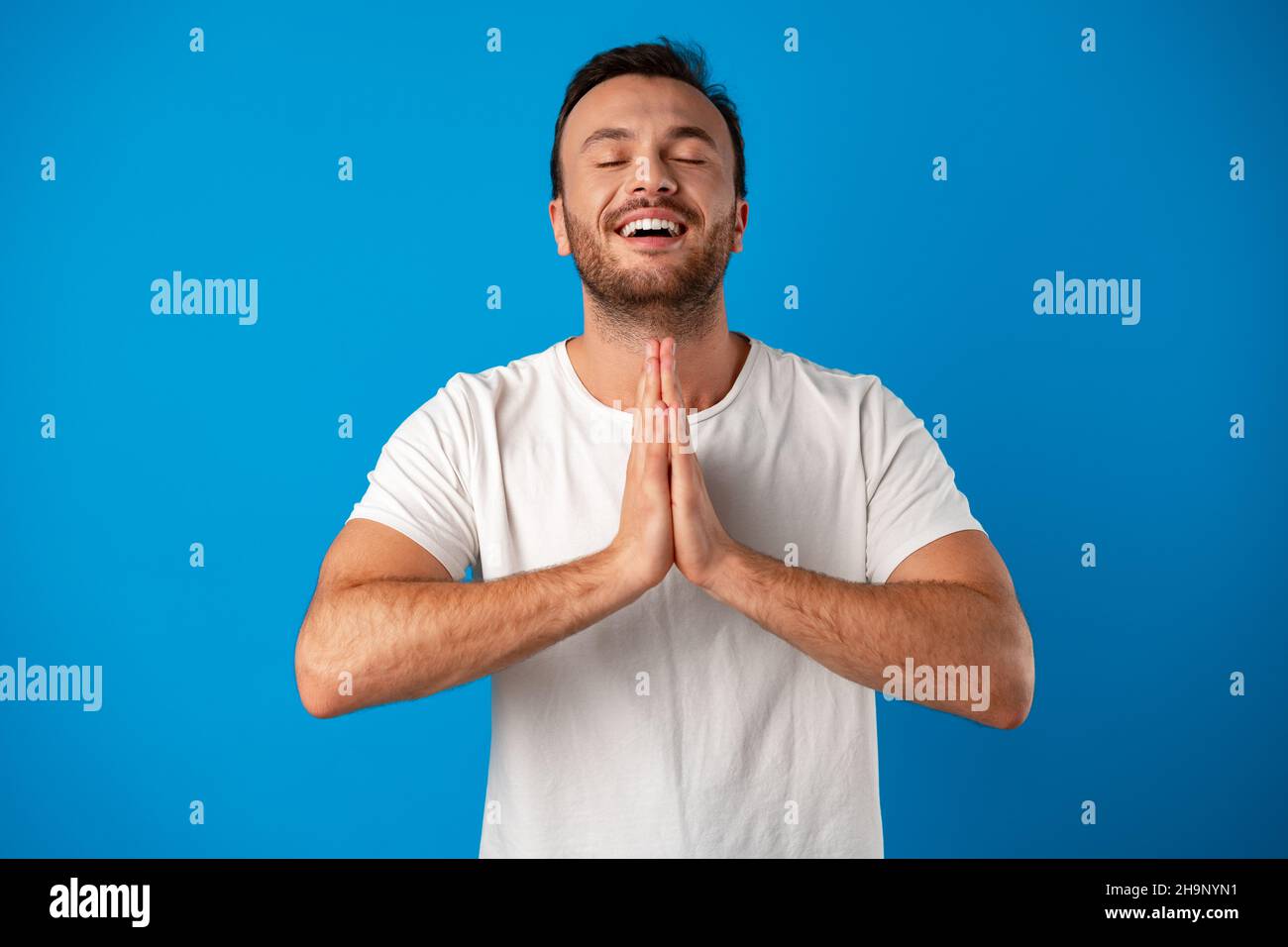 Focused handsome young man meditating on camera over blue background Stock Photo