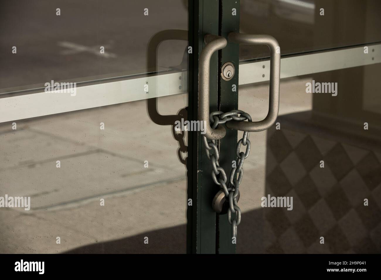 Chains lock together an entry way door of a closed business. Stock Photo