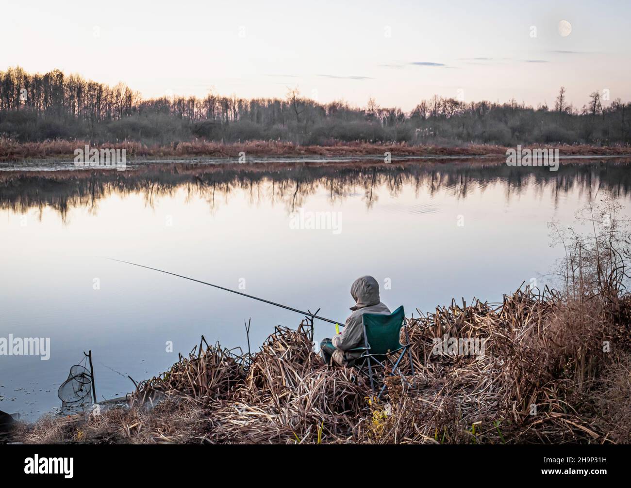 Autumn fishing in the morning on a forest lake under the waning moon Stock Photo