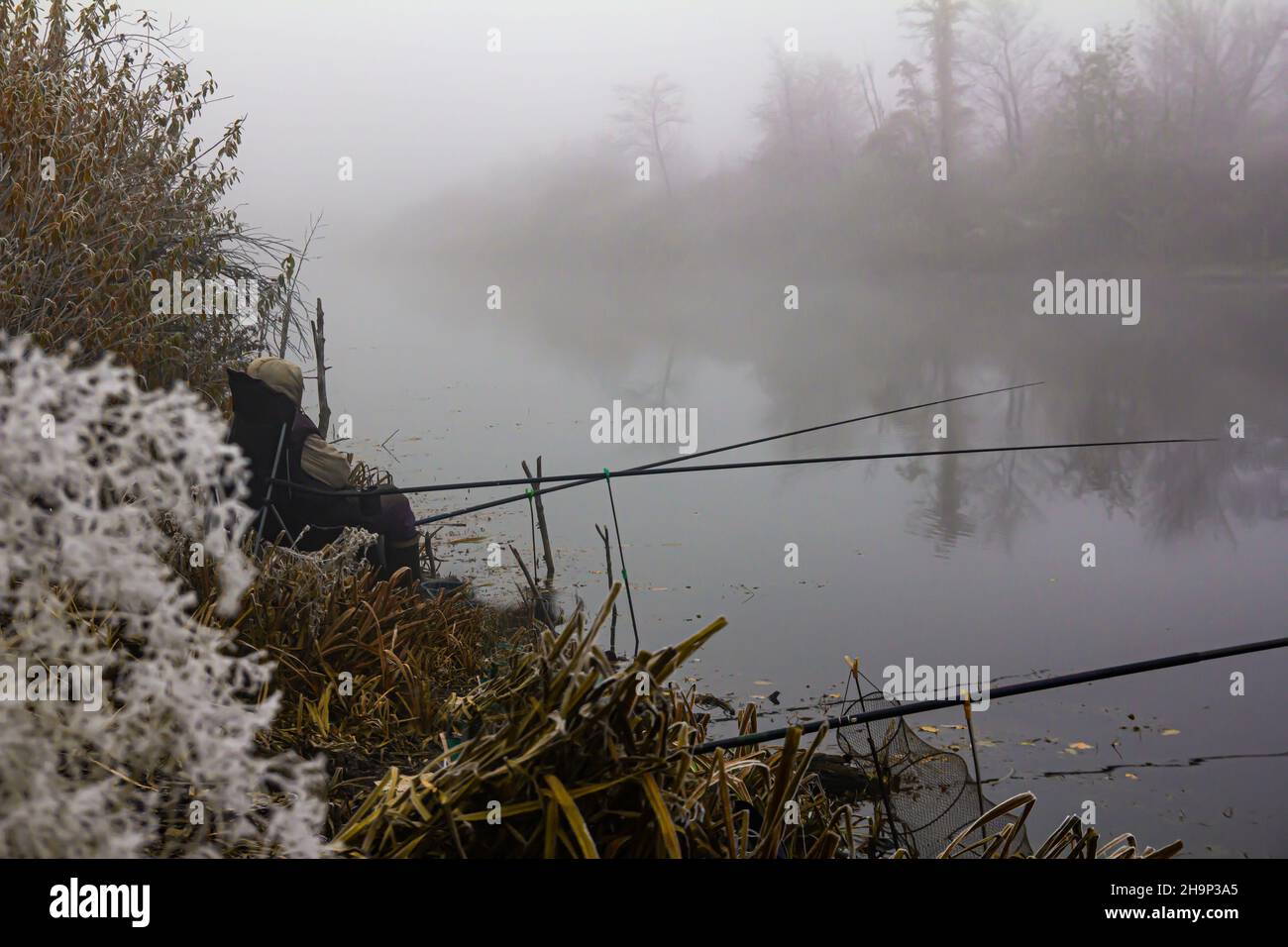 fishing on a foggy morning on a forest lake in late autumn Stock Photo