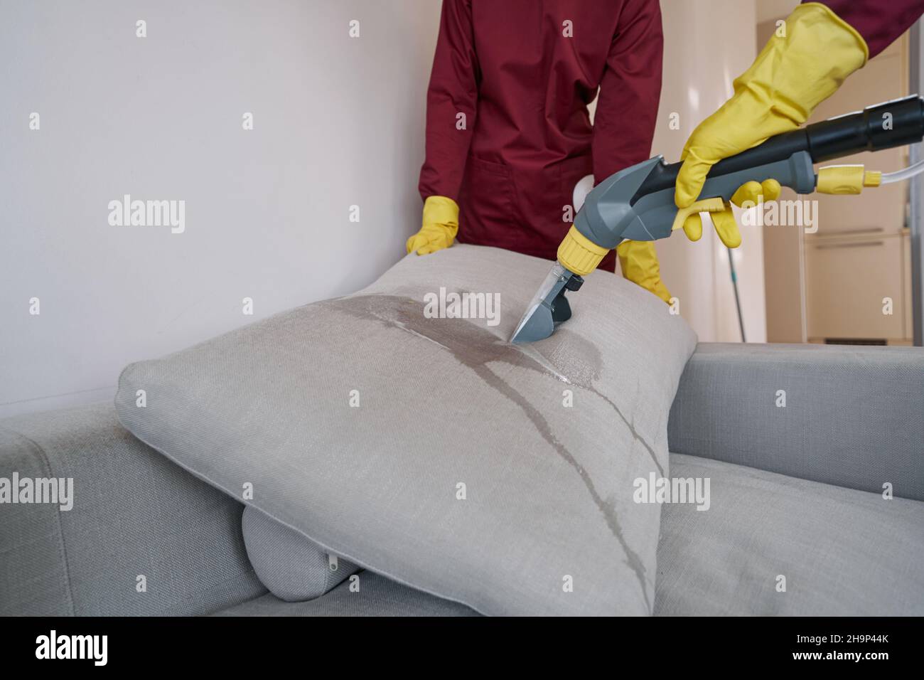 Two workers in rubber gloves steamcleaning couch pillow Stock Photo