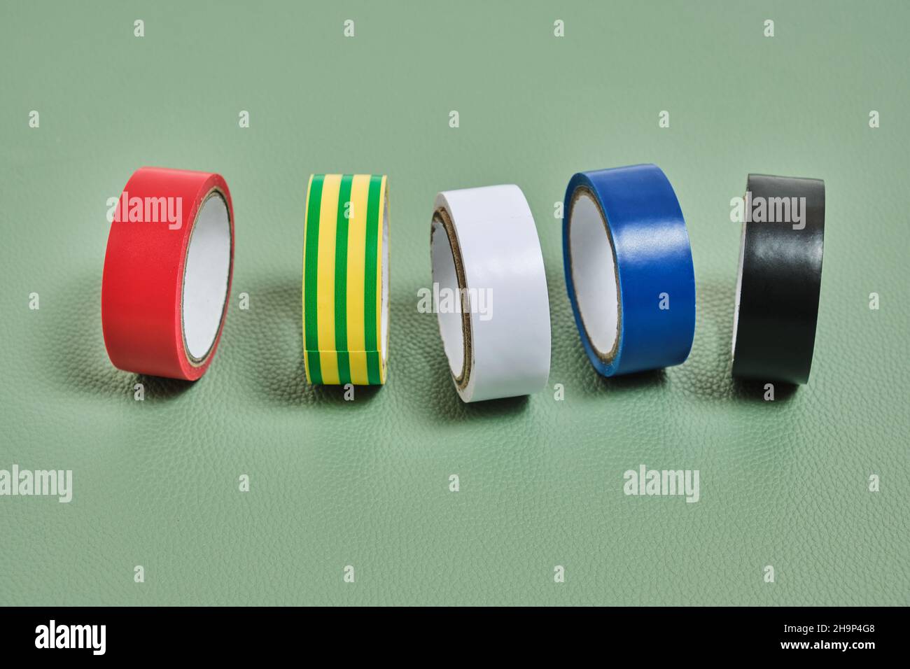Set of multicolored insulating adhesive tape on green background Stock Photo