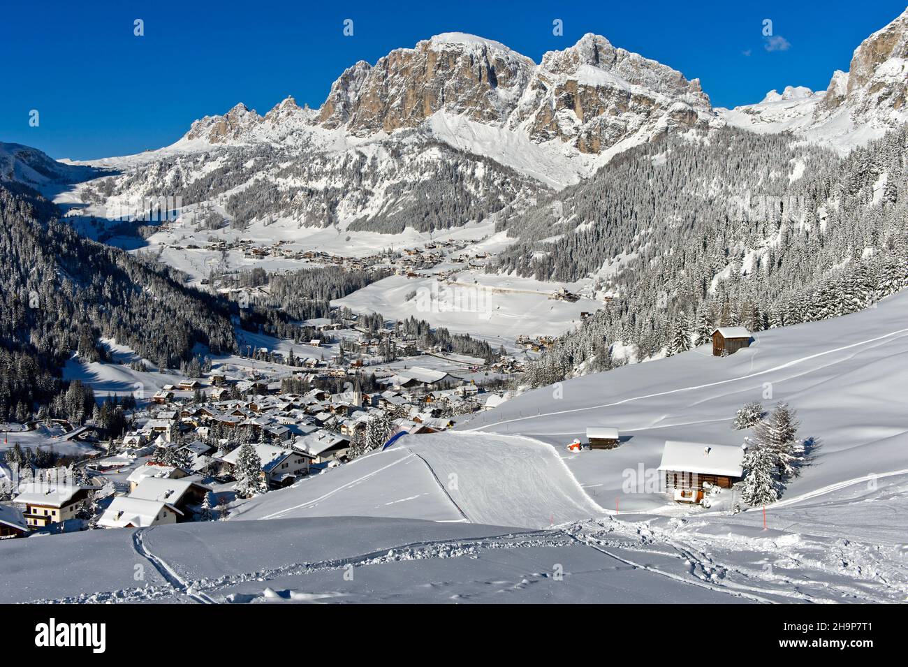 Empty ski slopes near the mountain village of La Villa in front of the snow-covered Dolomite peaks, Alta Badia ski area, Dolomites, South Tyrol, Italy Stock Photo