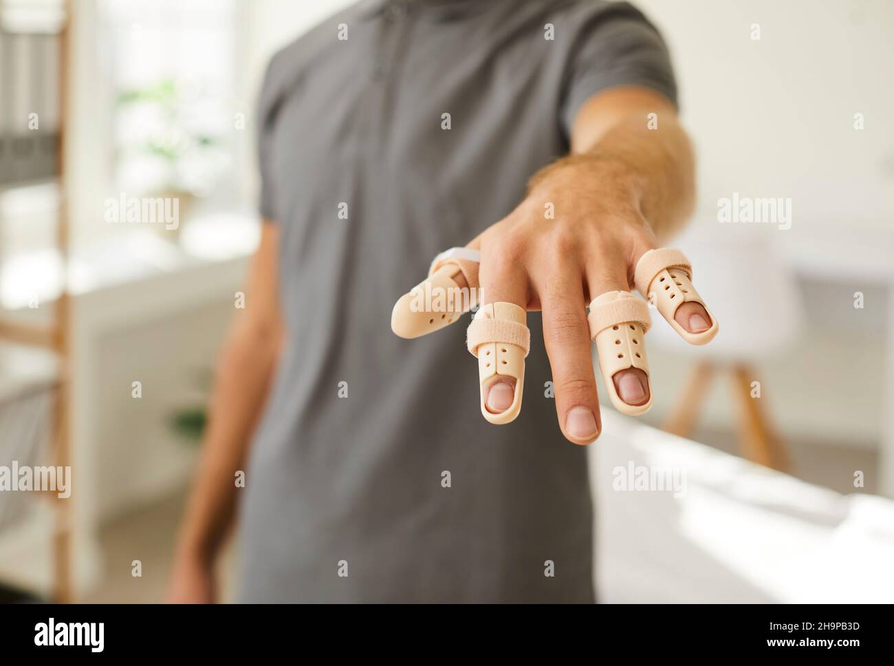 Man who has injured his fingers is showing his hand with adjustable finger support braces Stock