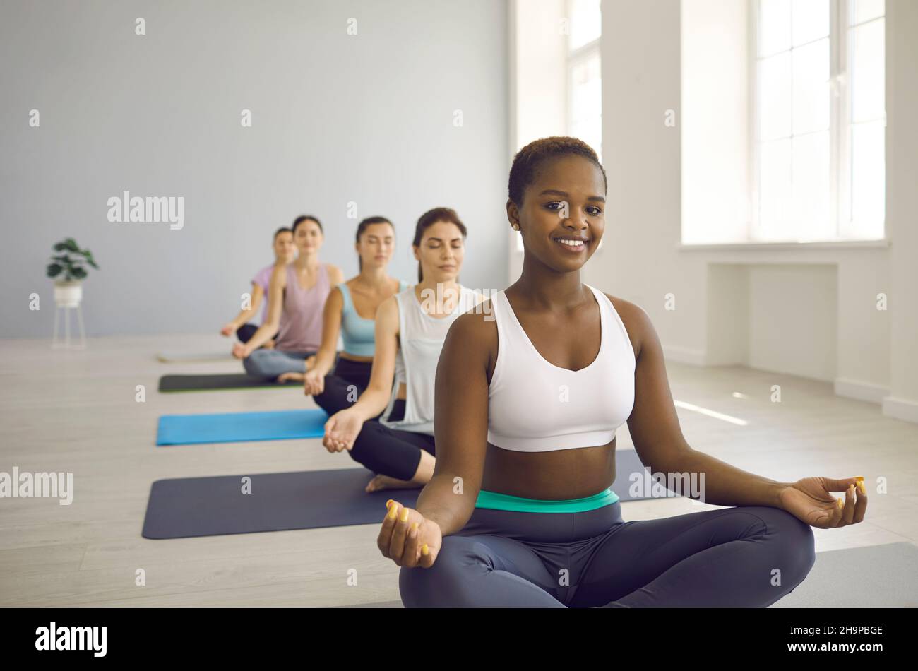 Active African American woman practicing yoga with other women in morning group training. Stock Photo