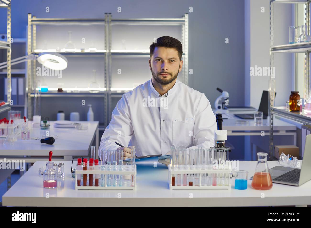 Portrait of a serious male scientist making notes while working on a new drug in a lab. Stock Photo