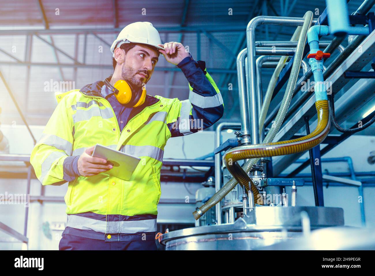 Factory worker Hispanic engineer working in factory checking maintenance pipe boiler system in factory. Stock Photo