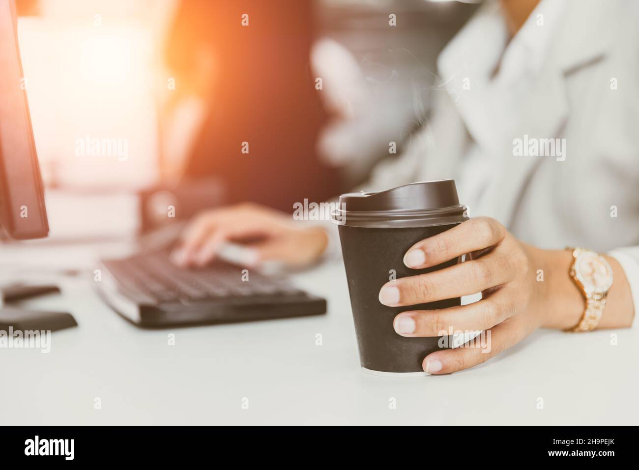 hand at coffee cup in office desk. business people drinking coffee from paper cup for good work concept Stock Photo
