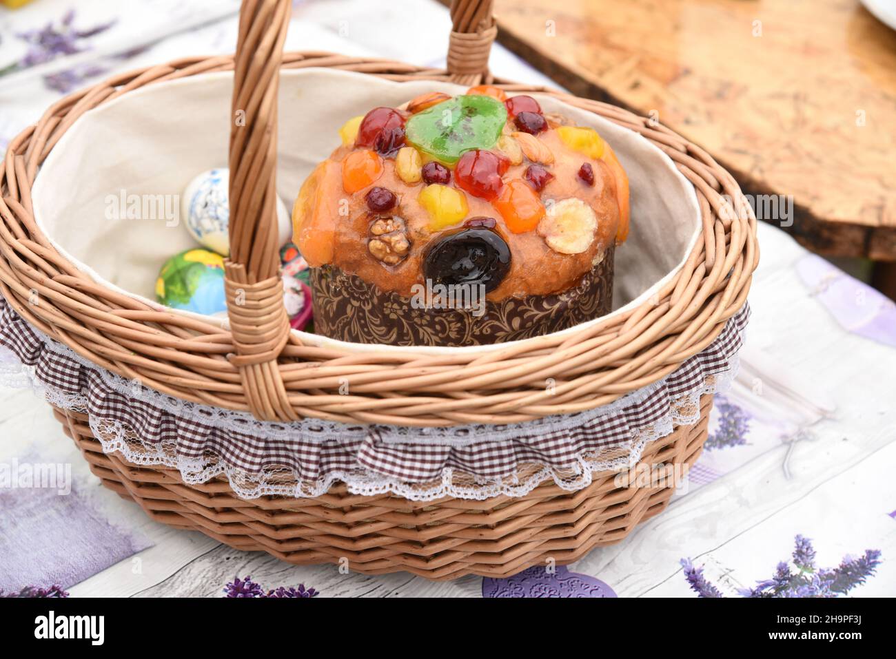 Decorated beautiful wicker Easter basket with Easter cake, painted eggs, treat Stock Photo