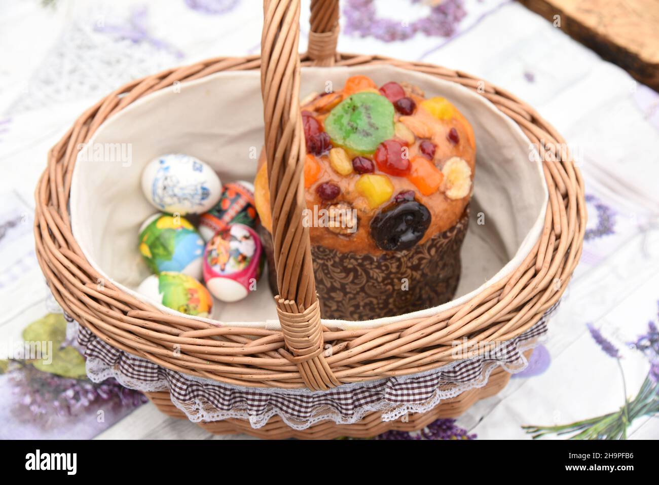 Decorated beautiful wicker Easter basket with Easter cake, painted eggs, treat Stock Photo