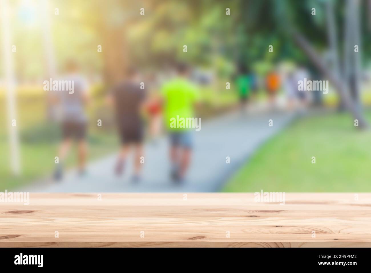 Blur people running in the park with wooden table top foreground for sport products montage background Stock Photo