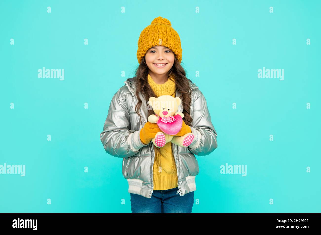 happy kid in puffer jacket and hat. childhood. teen girl hold toy bear. Stock Photo