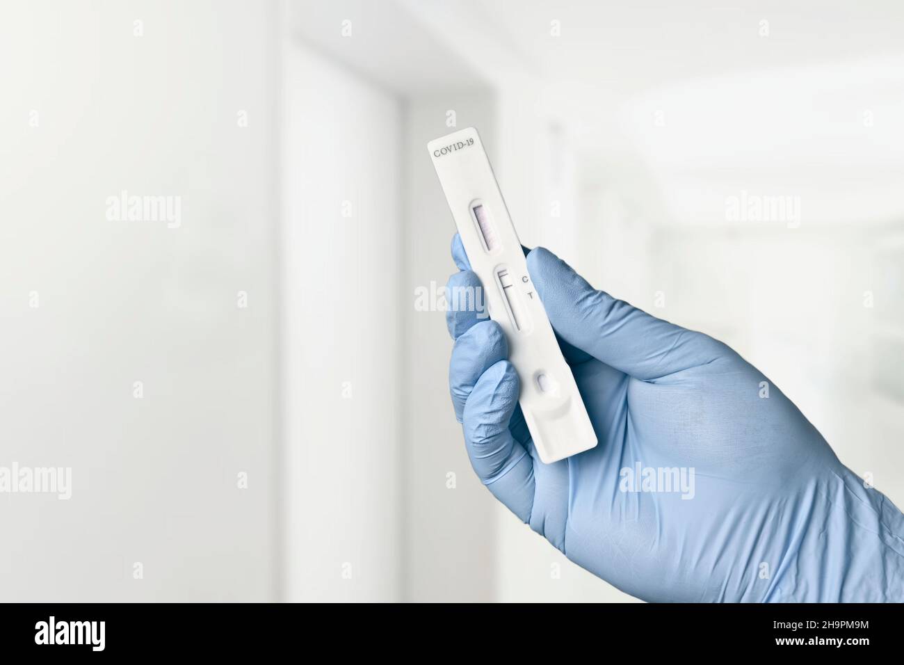 Gloved hand holding a negative rapid test device for COVID-19 in the hospital. Stock Photo