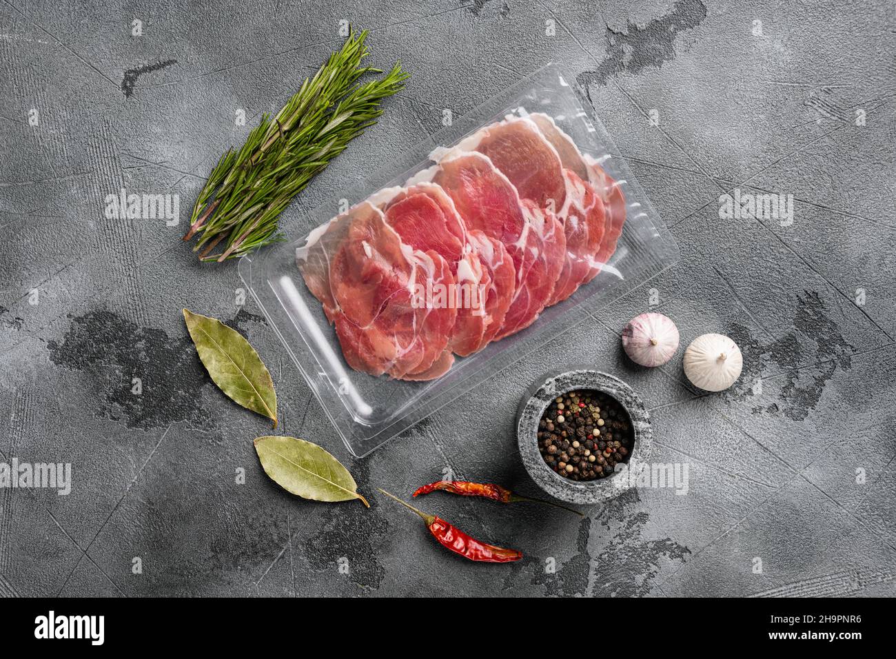 Vacuum packed serrano ham set, on gray stone table background, top view