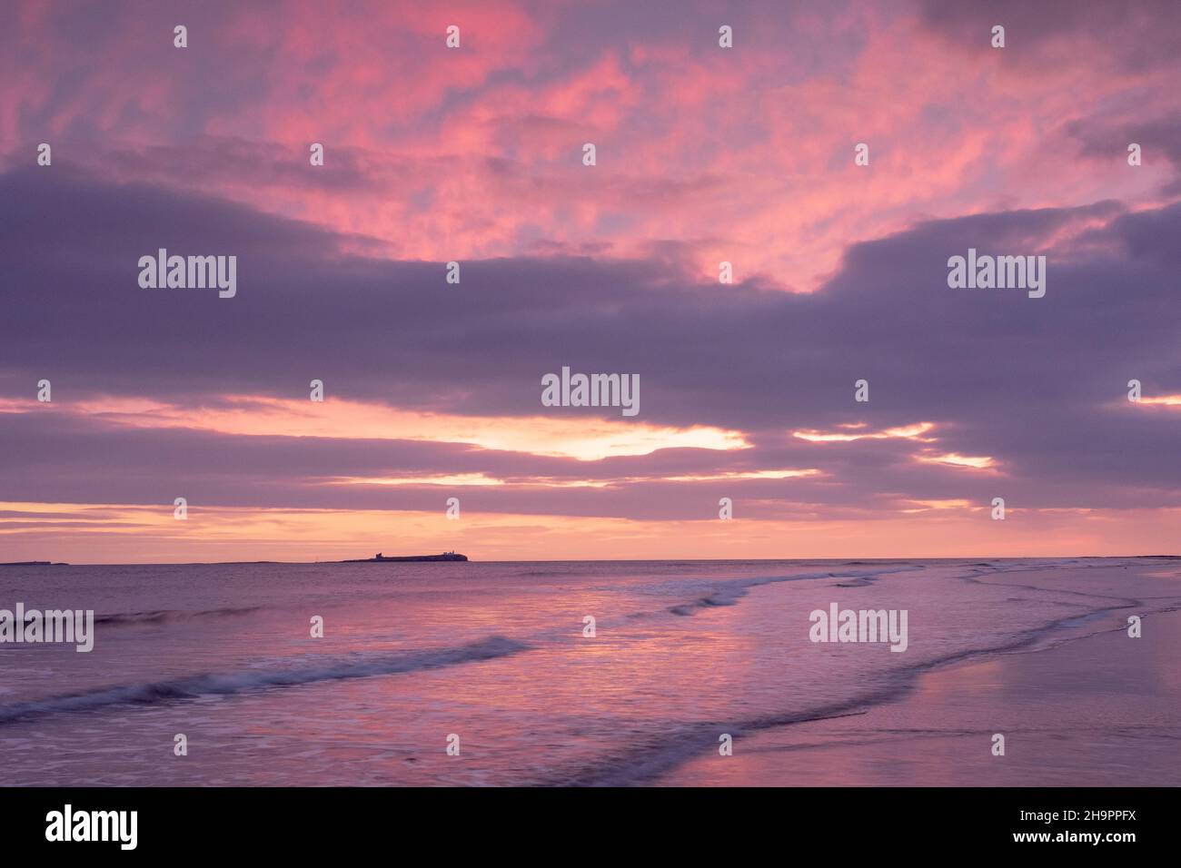 Dawn breaking over Bamburgh beach and the Farne Islands, Northumberland, England. Stock Photo