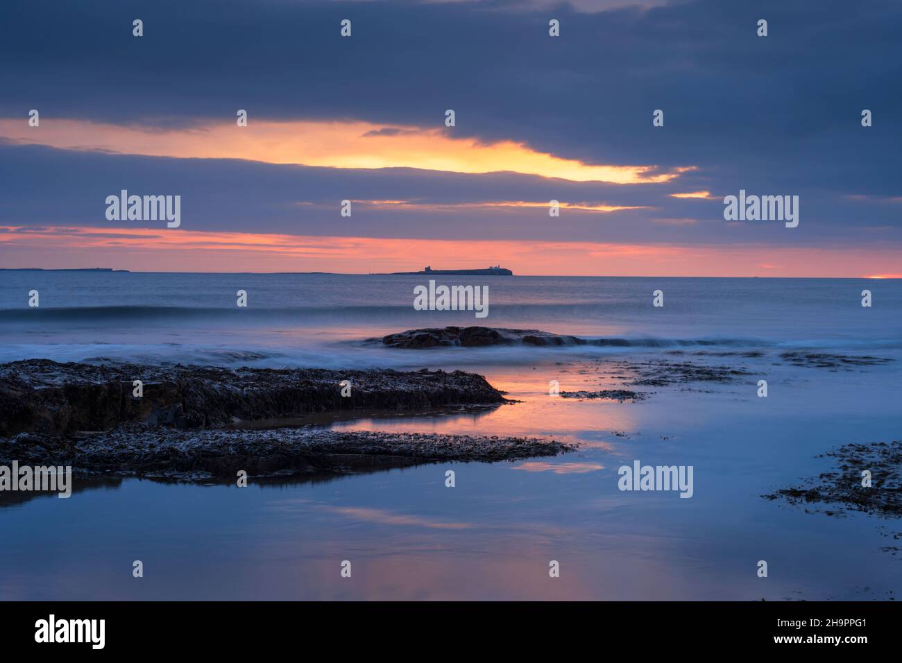Dawn breaking over Bamburgh beach and the Farne Islands, Northumberland, England. Stock Photo