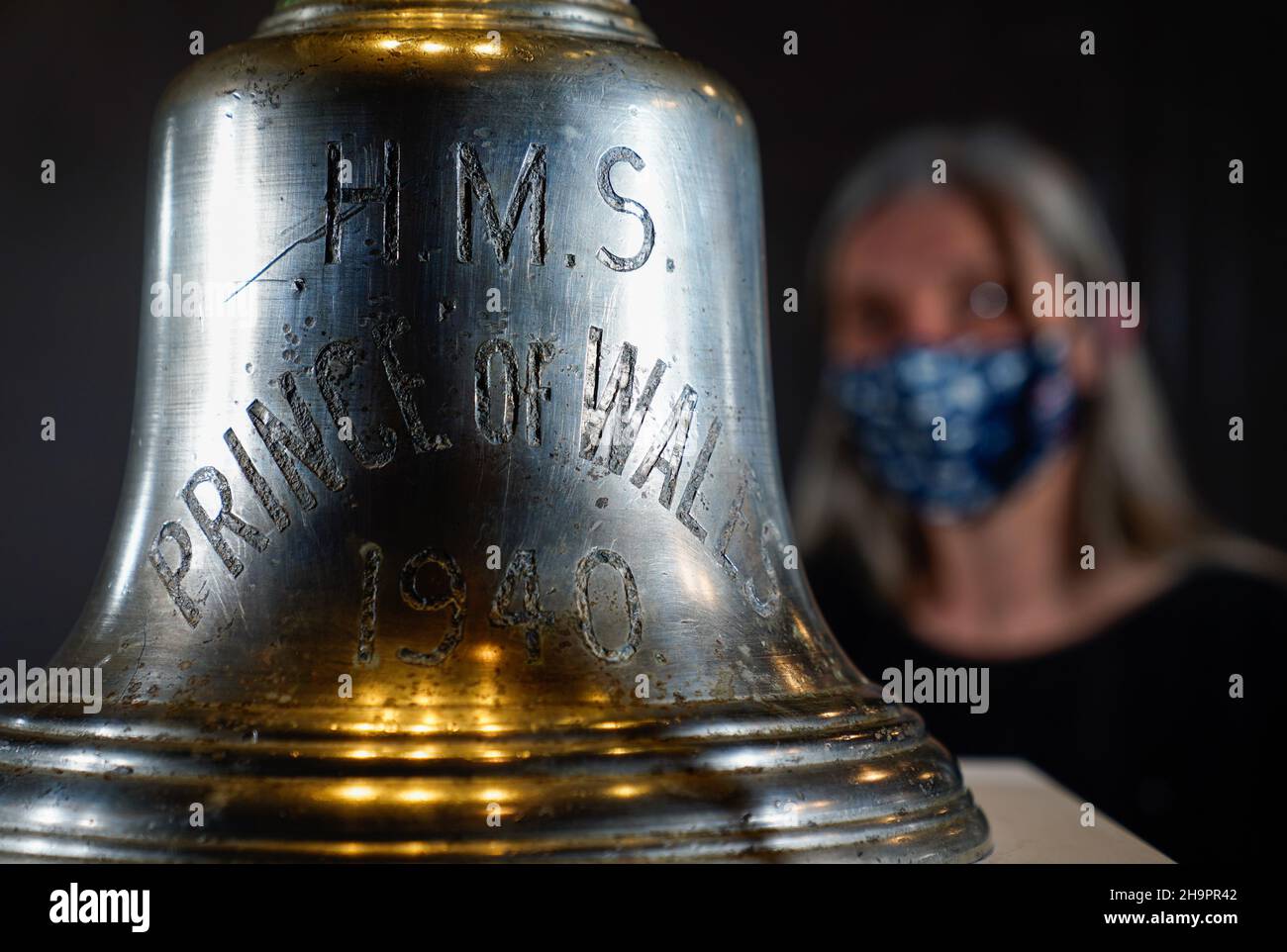 Victoria Ingles, senior curator at the National Museum of the Royal Navy, looks at the ship's bell from HMS Prince of Wales which was sunk along with HMS Repulse after a Japanese air attack on December 10 1941. 842 men lost their lives in what is one of the worst disasters in British naval history. Picture date: Wednesday December 8, 2021. Stock Photo