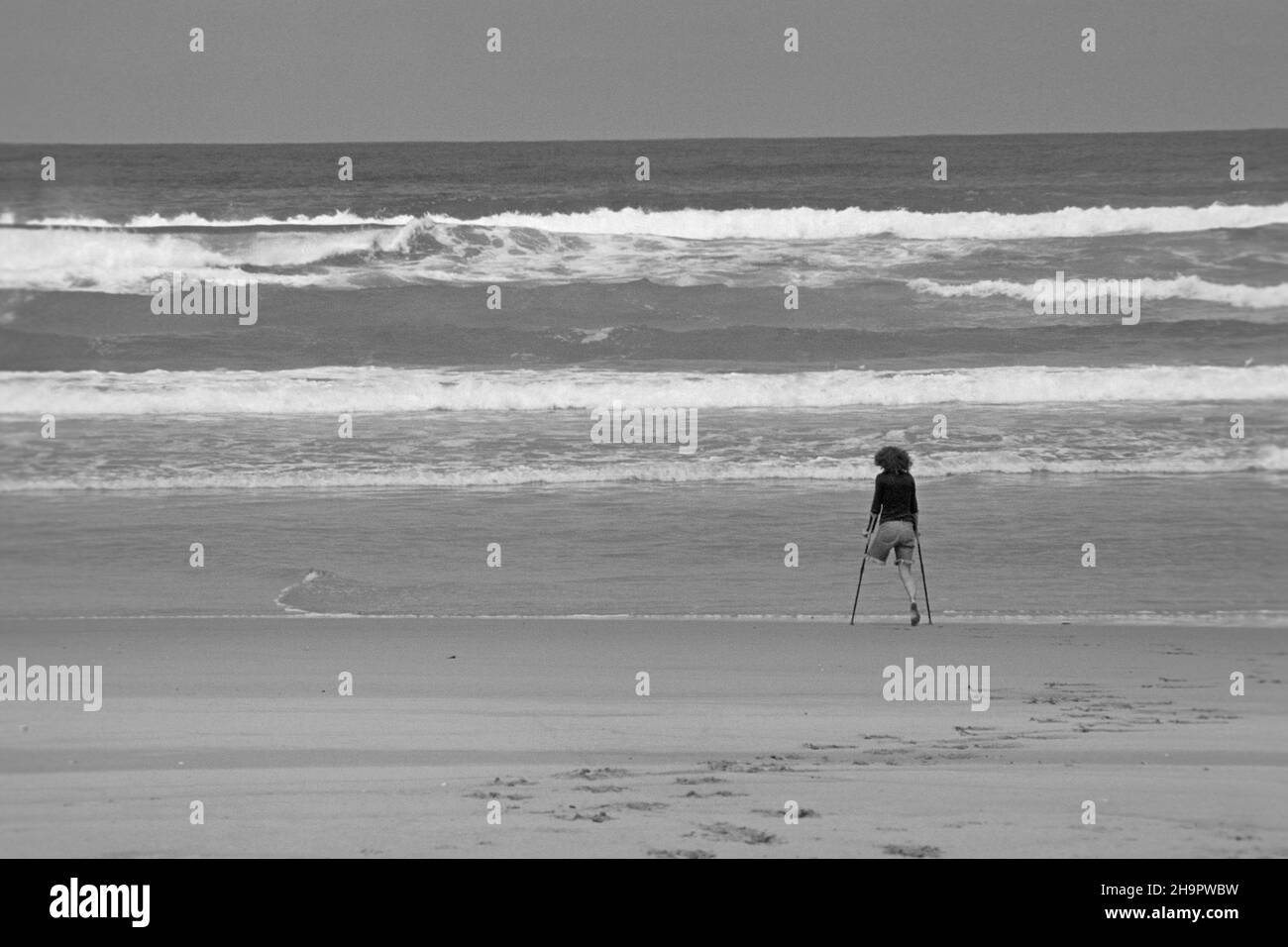 Onelegged young woman on crutches by the sea, onelegged, disabled