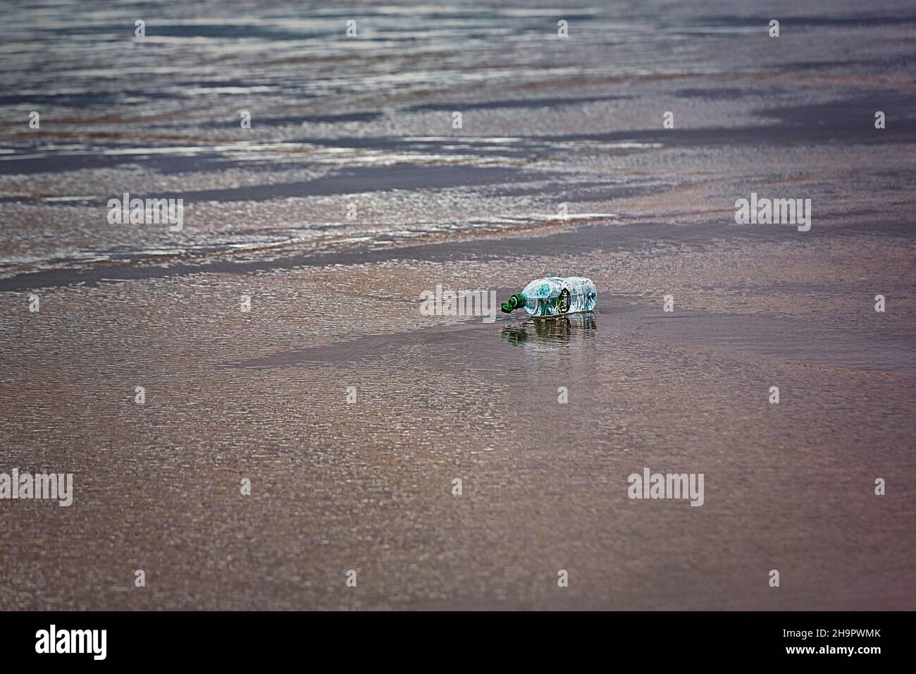Plastic bottle, Volvic brand water bottle lying on the beach, plastic waste, marine pollution, Ireland Stock Photo