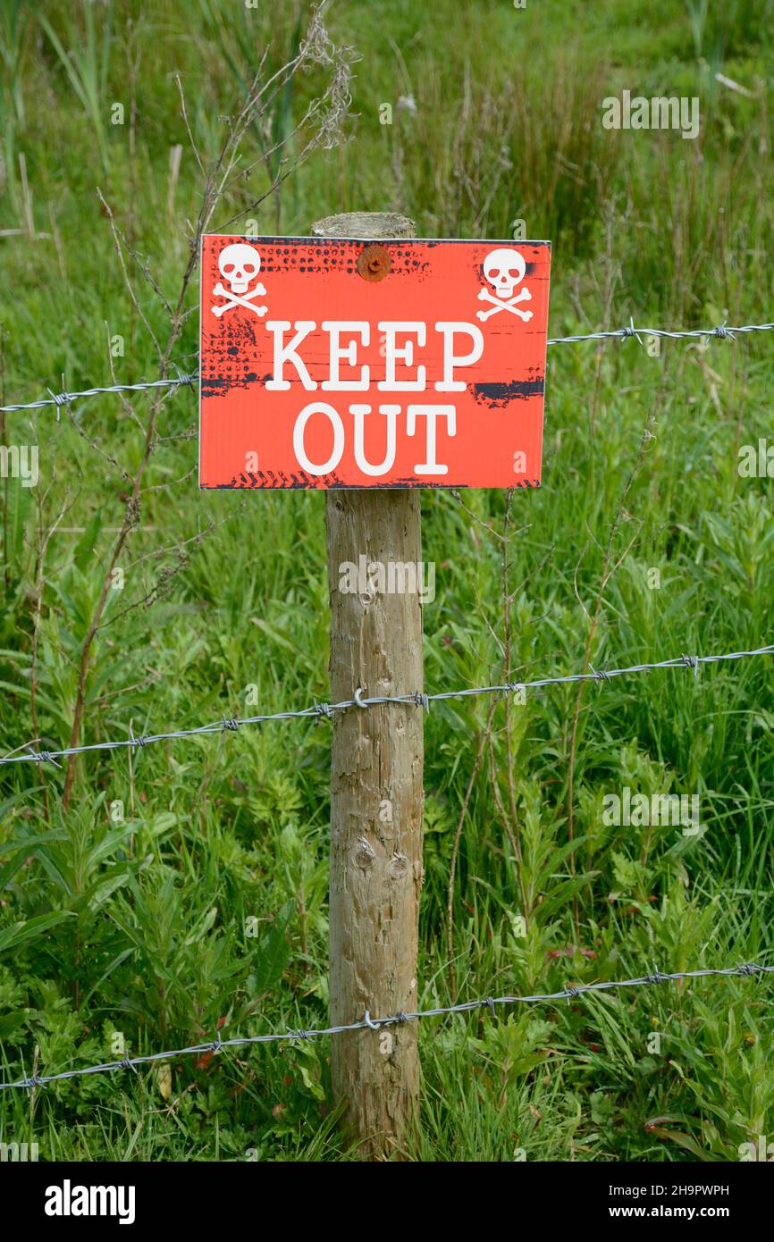 Keep Out sign fixed to a post on a barbed wire fence. Stock Photo