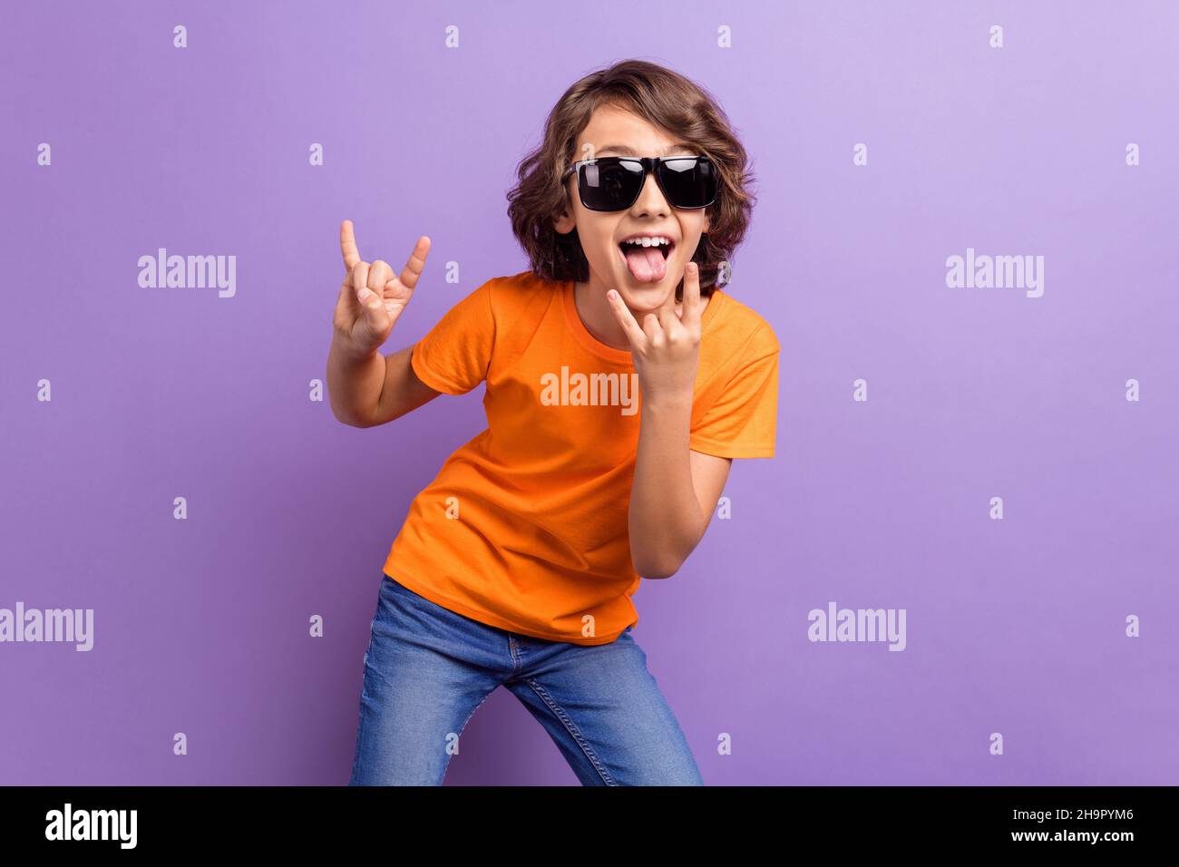 Photo portrait schoolboy in sunglass showing tongue heavy metal sign isolated pastel purple color background Stock Photo