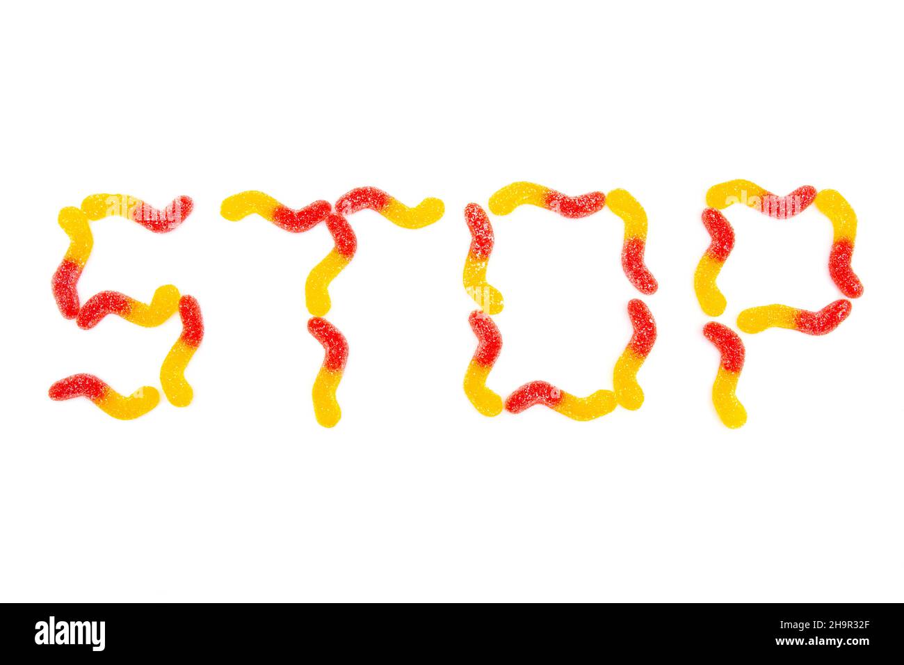 Word STOP made from multicolored gummy worms isolated on white background. Dental problems from chewy candies. Stock Photo