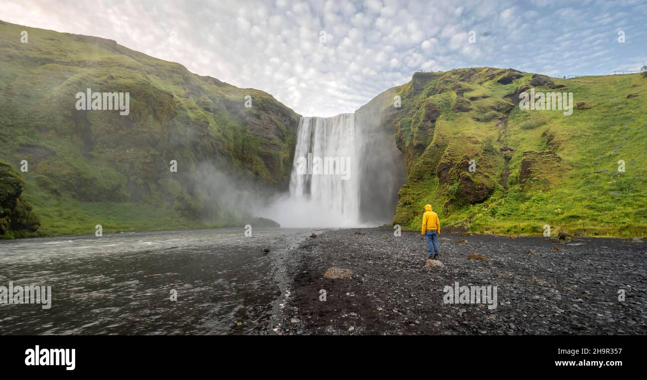 Huge waterfall behind a person, Skogafoss waterfall, South Iceland, Iceland Stock Photo