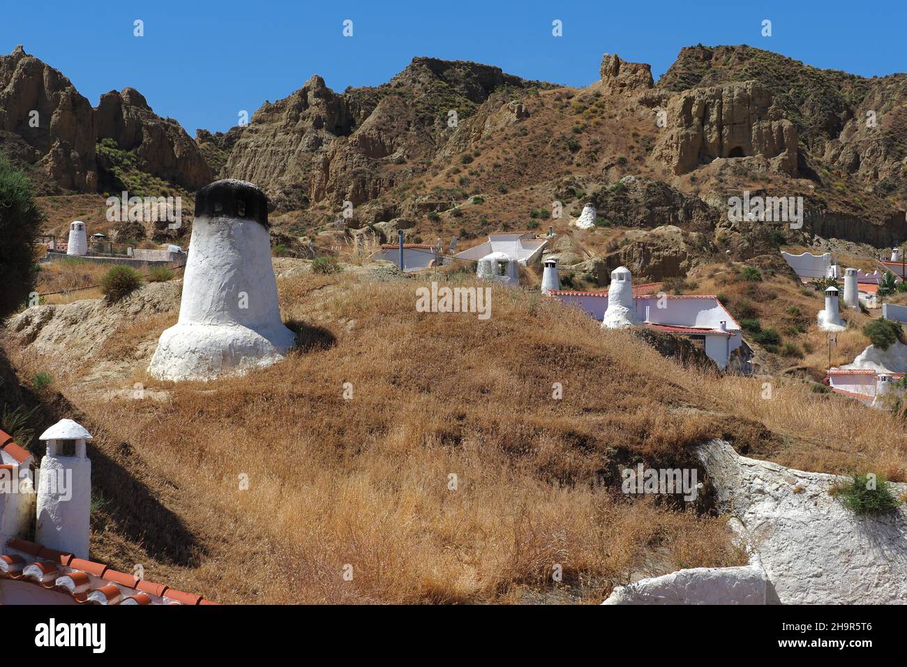 Cave houses in Guadix, White cave houses with chimneys in cave district of Guadix, fireplaces in earth, dwellings on the mountain, limestone tuff Stock Photo