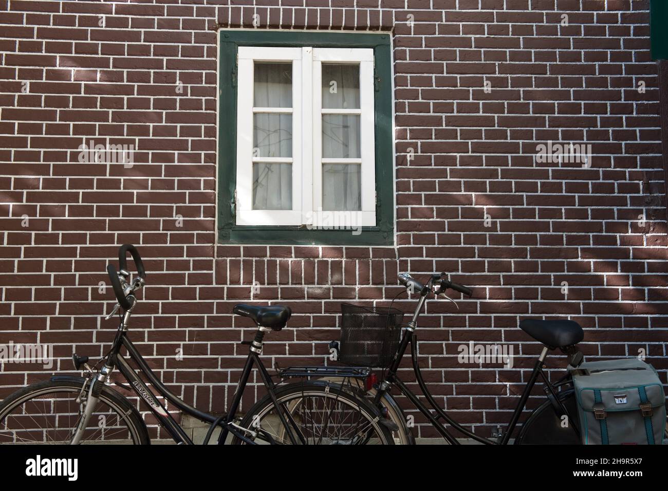 Dutch bikes leaning against red brick wall, brick, Frisian house, Frisian tradition, cycling, East Frisia, Dutch bike leaning against house wall Stock Photo