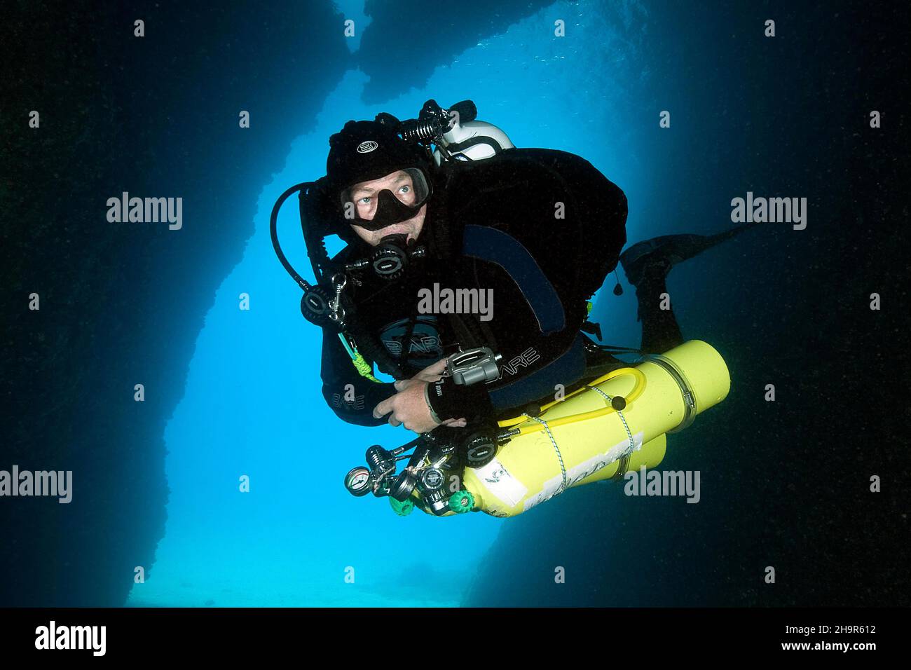 Diver does cave dive wearing special equipment with stage tanks, mixed
