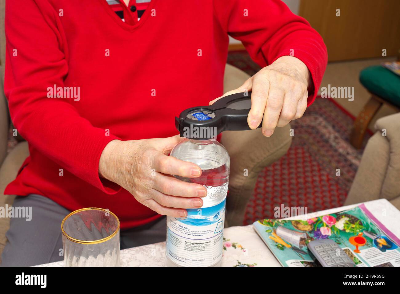 Old woman, senior citizen, 84 years, opening a water bottle with an