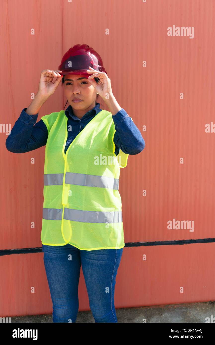 Portrait of a woman wearing a reflective vest and a safety helmet in a