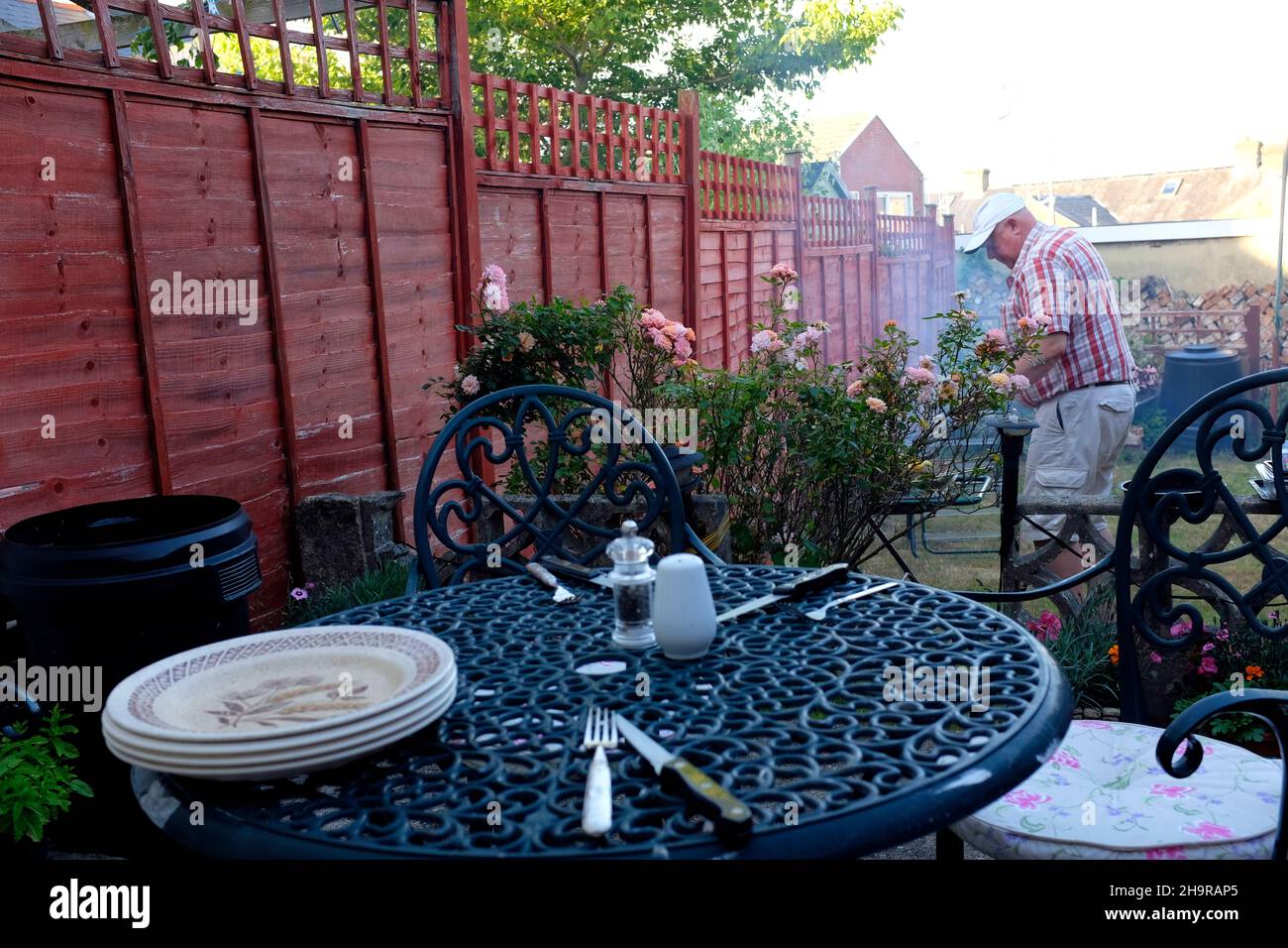 garden,barbi,barbeque,table,man,cooking,narrow,back,plates,cutlery, Cowes,Isle of Wight,England,UK, Stock Photo