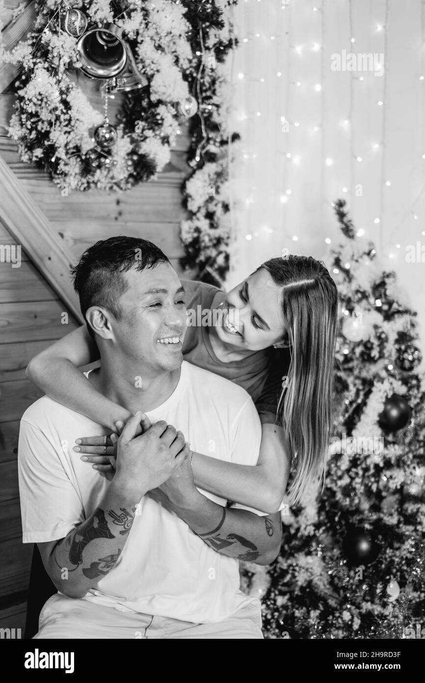 Black and white portrait of lovely couple. New Year's photo of happy couple. Cuddling, smiling and looking at each other. Love and happiness concept.  Stock Photo