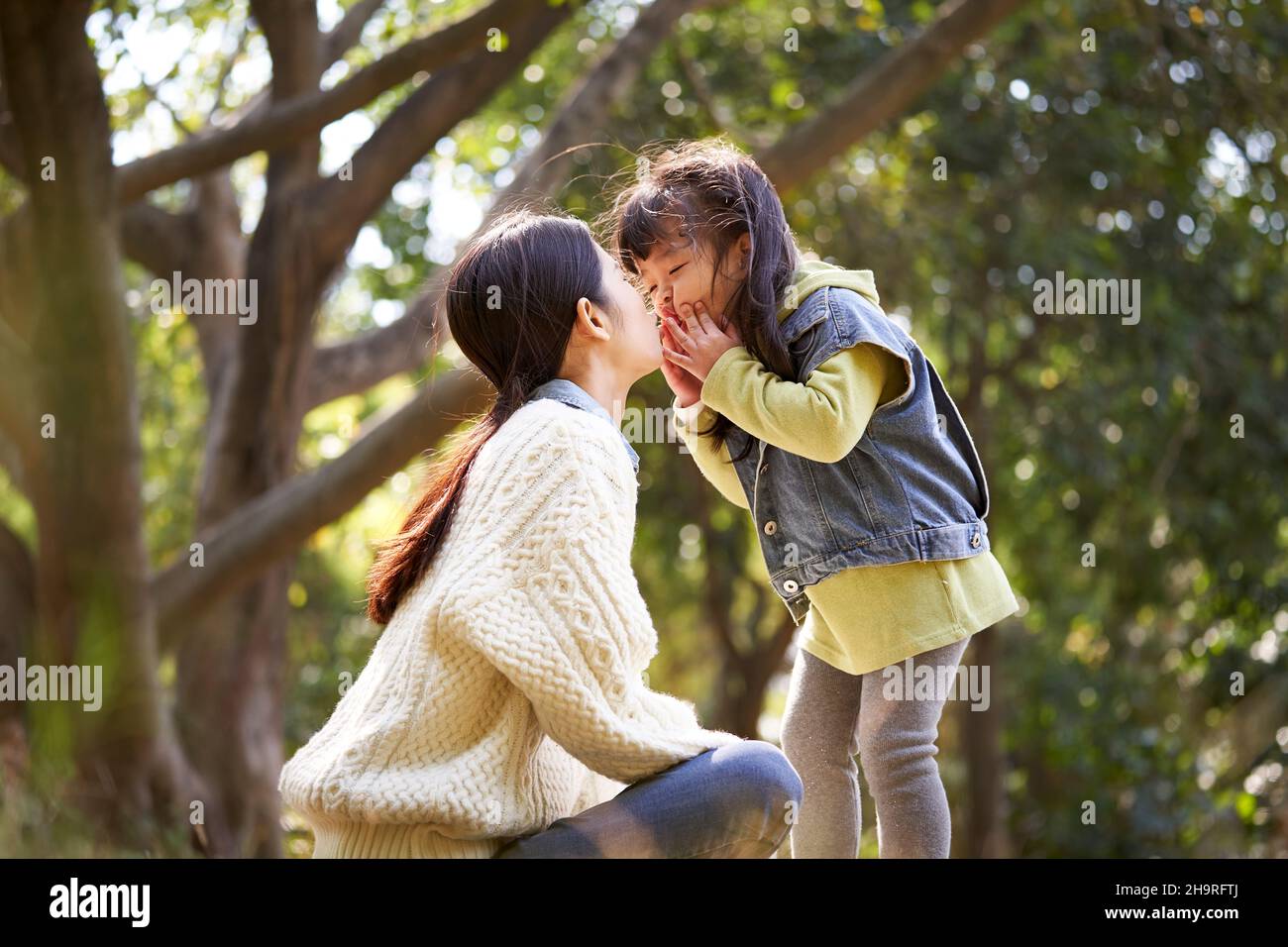 asian mother and daughter having a good time outdoors in city park Stock Photo