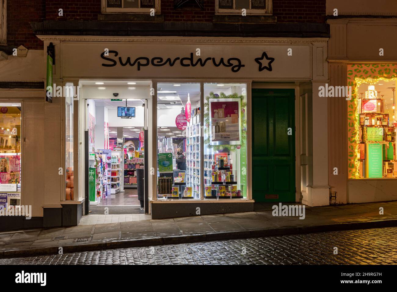 Superdrug shop front, health and beauty retailer, on Guildford High Street, Surrey, England, UK, at night Stock Photo
