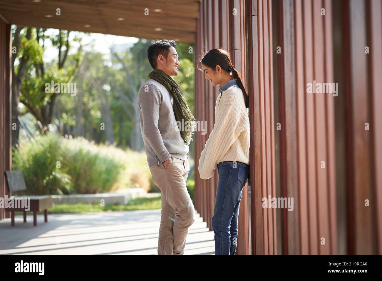dating young asian couple talking chatting outdoors in city park Stock Photo